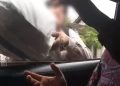 Foto: Tangkapan layar video viral, seorang perempuan menyerahkan uang yang dibungkus karung ke dalam mobil.